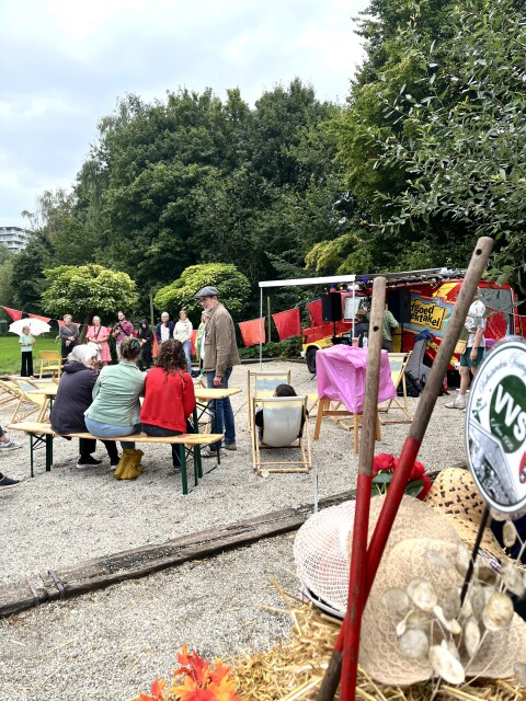Een overzichtsfoto van het geheel, het ziet er gezelllig uit en mensen zijn druk met elkaar in gesprek.
